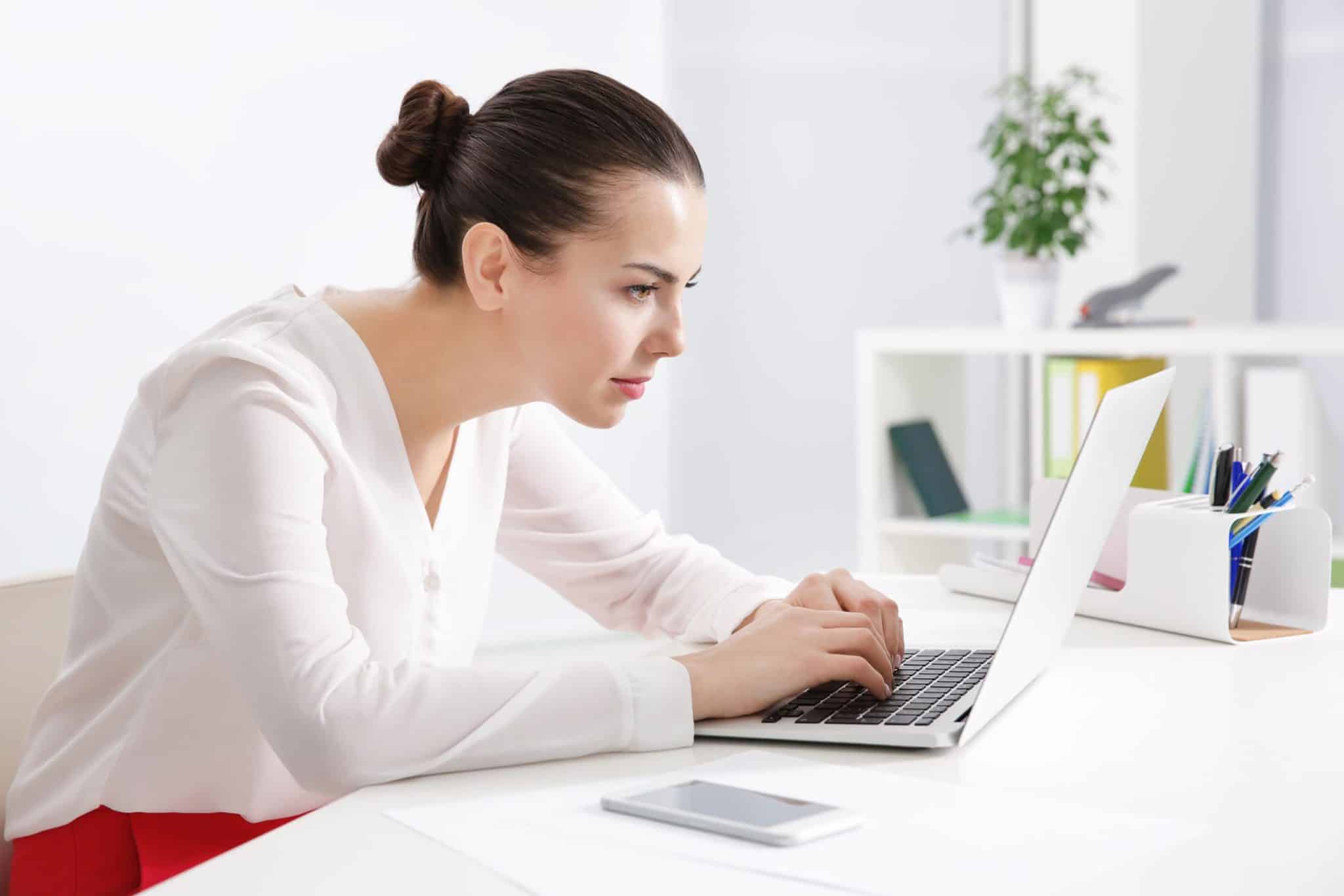 woman hunched over computer with poor neck posture which causes "tech neck"