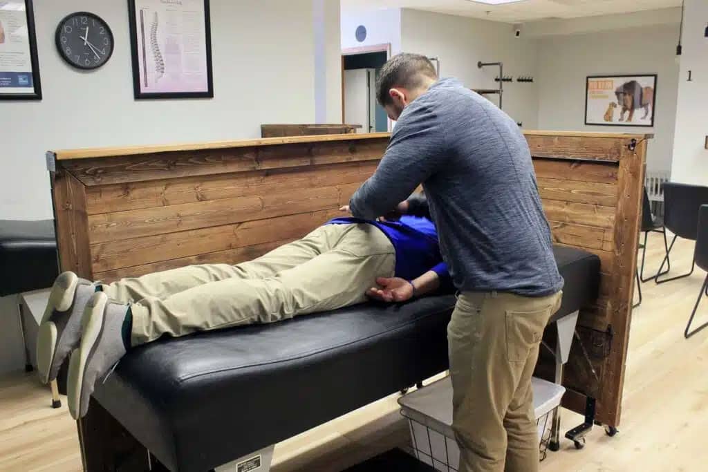 Chiropractor Dr. Evan is examining the patient's spine, who has back pain in New Berlin, WI.