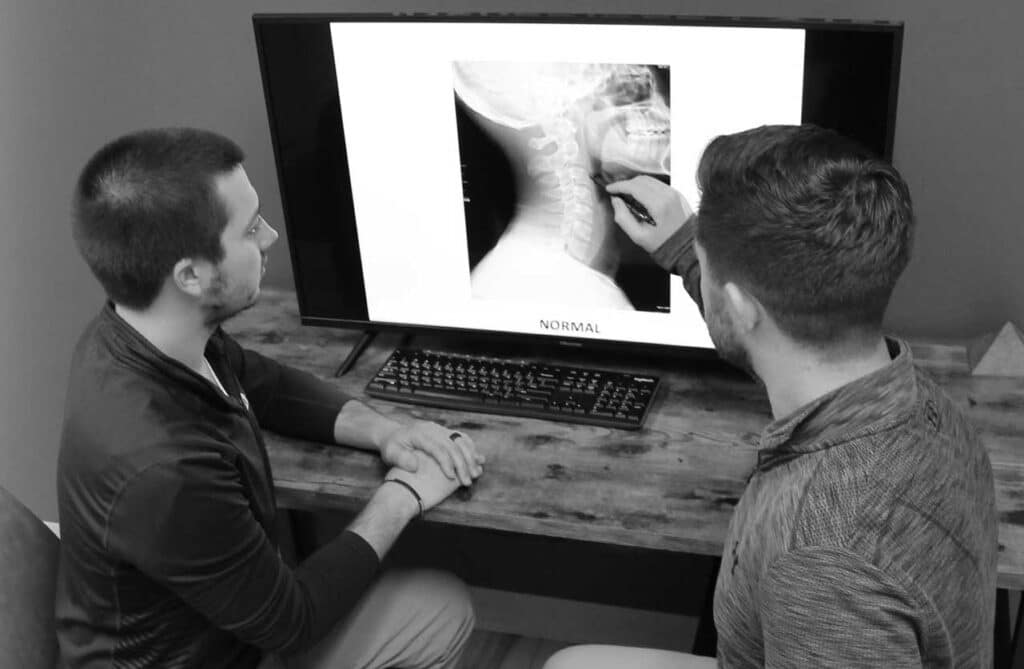 A group of chiropractors are examining x-rays of a patient who is experiencing neck pain in New Berlin, WI.