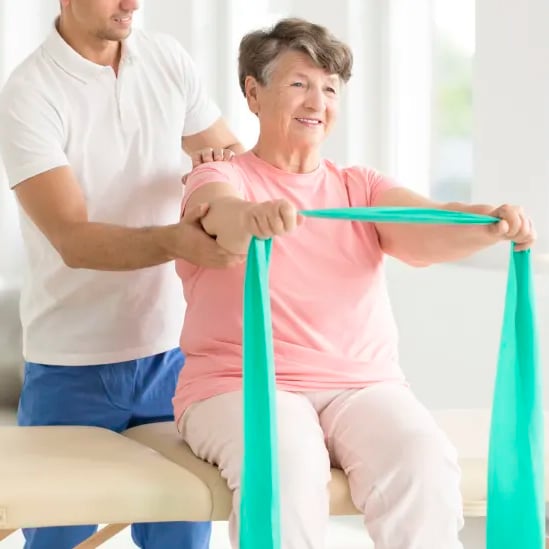 An elderly patient using green resistance bands with the aid of her Chiropractor in Brookfield.