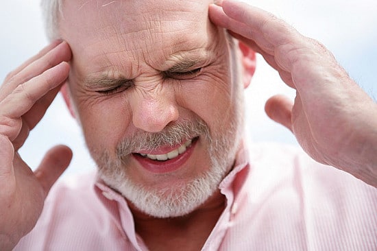 Man suffering from a migraine headache holding his temples.