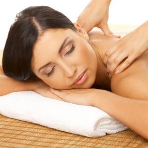 A girl laying down getting her shoulders massaged.