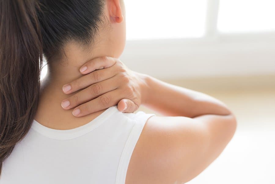 Woman with neck pain holding her neck.