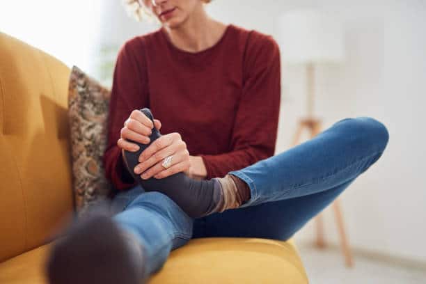 Woman with neuropathy holding her foot.