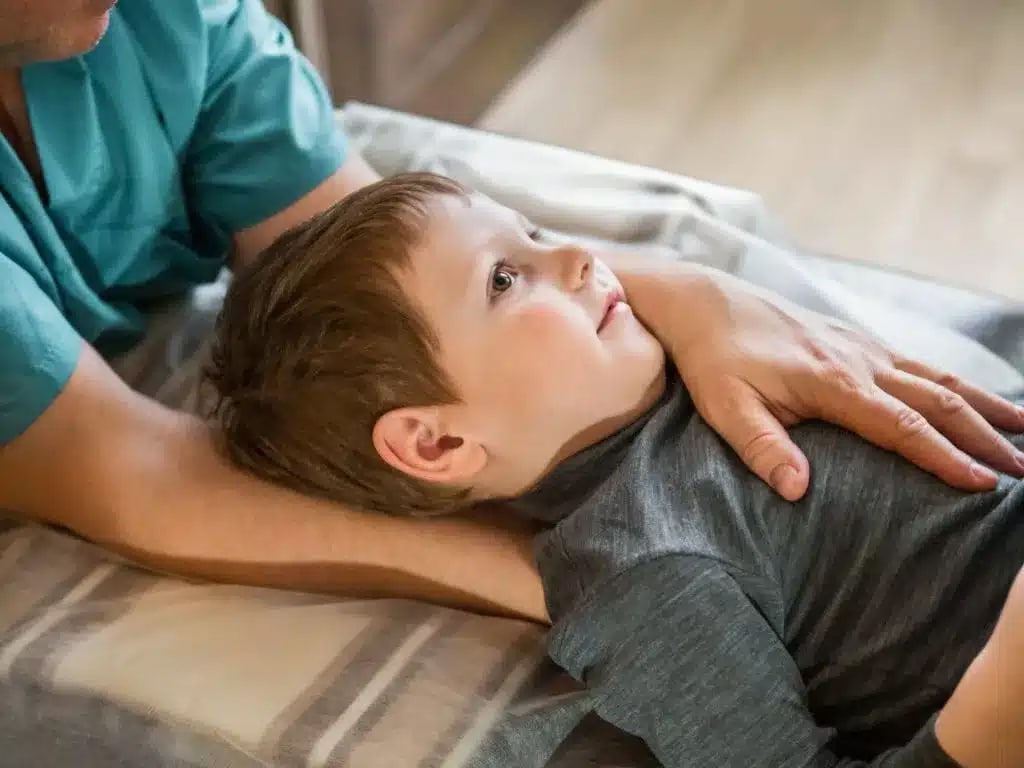 Child laying down with a chiropractor holding his chest.
