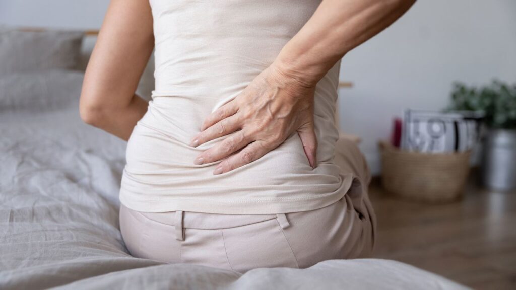 Elderly woman holding her back because of sciatic nerve pain.