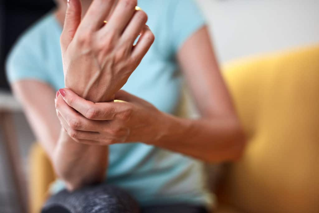 woman holding hand in pain getting neuropathy benefits