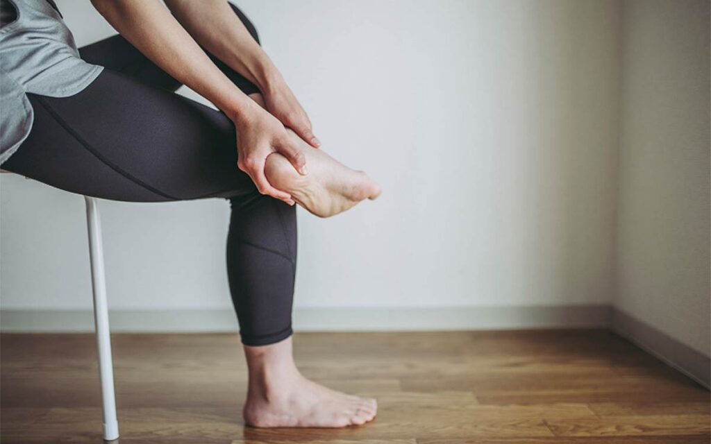 woman holding foot with neuropathy